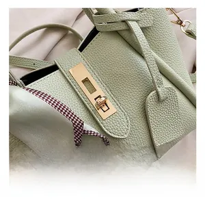Dettaglio borsa in pelle verde con chiusura dorata e foulard di seta a motivi pied de poule