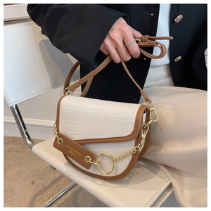 Detail of crocodile embossed leather saddle bag with gold ring buckle and chain strap