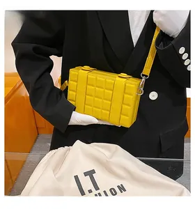 Detail of bright yellow quilted checkered crossbody box bag with silver hardware