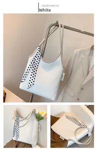 Detail of white ruched shoulder bag featuring a polka dot ribbon and fashion tag