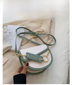 Detail of white crocodile pattern saddle bag with green trim and gold chain hardware