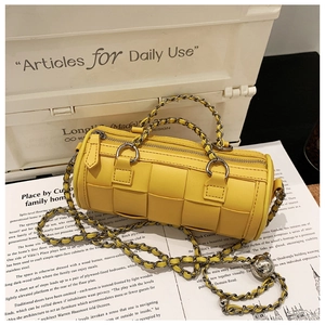 Detail of yellow woven barrel bag with chunky metal chain and gold sphere charm