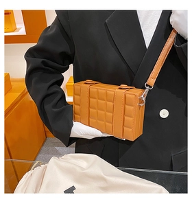 Detail of a brown plaid quilted crossbody box bag with leather strap and silver hardware