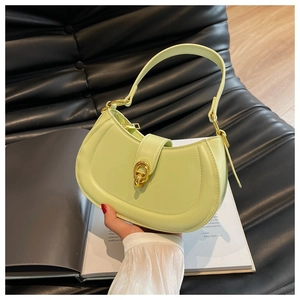 Detail of light green leather handbag with gold metal clasp on a black sofa