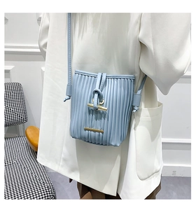 Detail of light blue pleated bucket bag with gold horn clasp and long crossbody strap