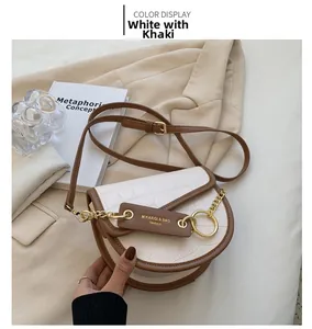 Detail view of white croc-effect saddle bag with khaki trim and gold chain accessory