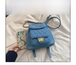 Mini sac à dos en denim bleu matelassé avec fermoir doré posé à côté d'un téléphone