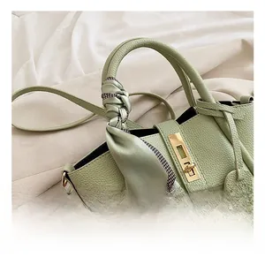 Dettaglio borsa a mano verde menta in pelle martellata con chiusura dorata e foulard