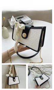 Detail of retro cream handbag featuring embossed patterns, black leather trim and silk scarf