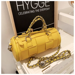 Detailed view of yellow woven cylindrical bag with gold chain strap and metal ball buckle
