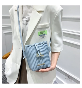 Close-up of light blue pleated bucket bag with gold buckle on a stylish model