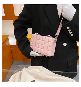 Pink box crossbody bag with quilted grid texture and adjustable shoulder strap worn by model