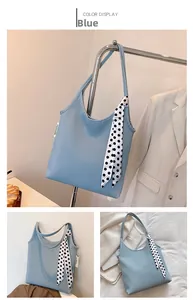 Detail of blue pleated tote bag with polka dot scarf handle and fashion label tag