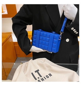 Detail of royal blue quilted box crossbody bag with silver clasp and thin shoulder strap