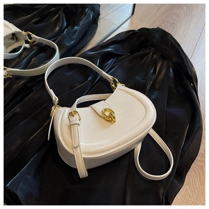 Macro shot of white semi-circular bag with gold chain buckle and fine leather texture