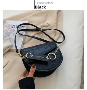 Detail of black crocodile embossed saddle bag with gold chain and leather strap