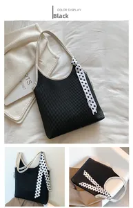 Detail view of black pleated shoulder bag with cream strap and polka dot ribbon decoration