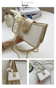 Detail of khaki shoulder bag with cartoon embossing and decorative silk scarf