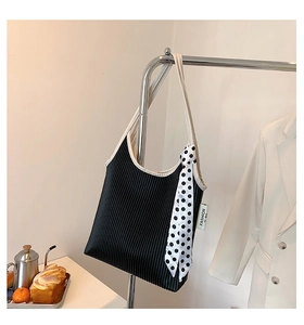 Detail of black pleated shoulder bag with polka dot scarf and fashion label