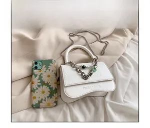 Detail of white leather bag with wavy edge and metal chain showing phone scale