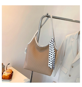 Detail of khaki pleated tote bag with white trim and a black and white polka dot scarf