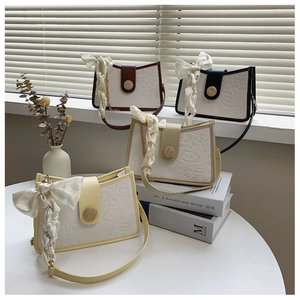 Detail of four colorful embossed faux leather shoulder bags with ribbons and wood buckles
