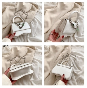 Detail of white embossed leather handbag with metal chain and flower charm accessory