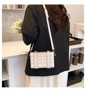 Chic beige quilted square crossbody bag styled with a modern black blazer and white skirt