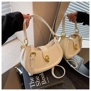 Detail of white saddle bag with golden metal hardware and a round twist lock closure