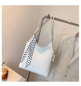 Close-up of white pleated shoulder bag with black and white polka dot ribbon detail