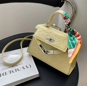 Vintage pale yellow embossed leather Kelly bag with silk scarf on designer chair
