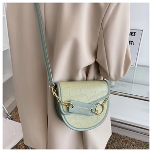 Close-up of olive green saddle bag with crocodile pattern and golden chain detail