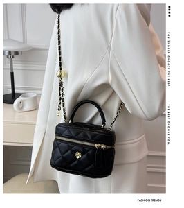 Detail showing black quilted leather bag with gold chain and camellia charm accent