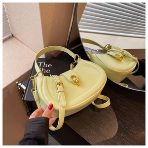 Detailed view of light green semi-circular handbag with elegant golden metal clasp and strap