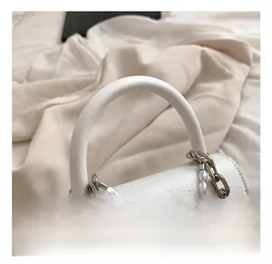 Detail of white leather handbag featuring chunky silver chain with pearl and green jade pendant