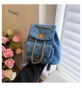 Détail du mini sac à dos en denim bleu matelassé avec chaîne dorée et fermoir pivotant
