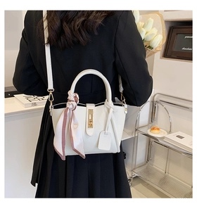 Dettaglio della borsa tote bianca con trama litchi, chiusura dorata e foulard a scacchi