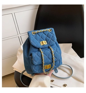 Détail du sac à dos en jean bleu avec coutures matelassées et chaînes dorées
