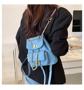 Détail d'un mini sac à dos en jean bleu clair matelassé avec bretelles en chaîne dorée