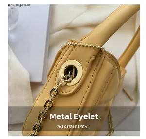 Detail shot of golden metal hardware and ball chain on a yellow leather handbag