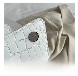 Détail du sac blanc à motif crocodile avec fermoir magnétique métallique circulaire