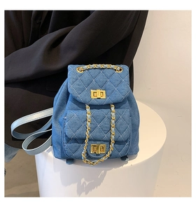 Détail d'un mini sac à dos en jean bleu avec chaîne dorée et fermoir pivotant sur socle