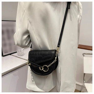 Detail of black faux crocodile saddle bag with gold chain and circular metal fastener