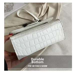 Détail d'un sac à main blanc à motif crocodile montrant la base résistante à l'usure