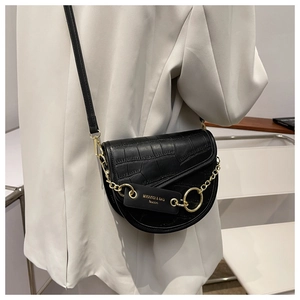 Detail of black croc-effect saddle bag with gold chain and circular metal buckle