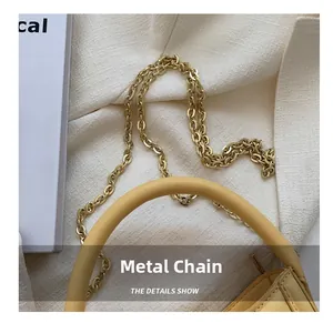 Detail of yellow fashion handbag with gold circular metal chain links and smooth leather