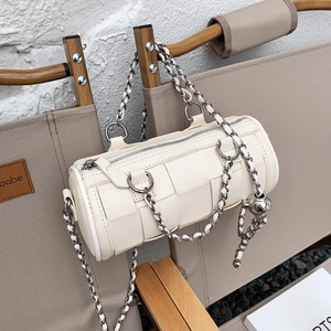 Chic beige woven cylinder bag with silver chain strap and metallic ball pendant