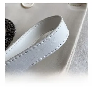 Détail de la bandoulière en cuir blanc avec coutures de qualité et chaîne métallique
