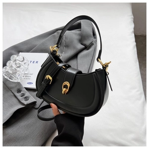 Detail of black leather saddle bag with gold metal buckle and smooth curved flap cover