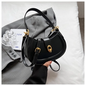 Detail of black matte crescent moon bag featuring gold hardware and adjustable strap